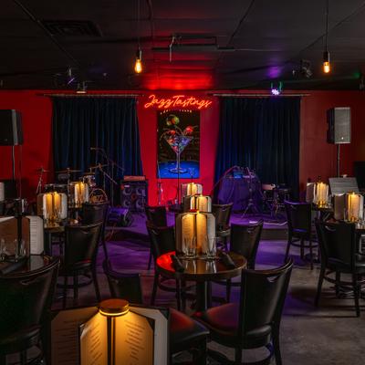 Interior, wide view to bar area, tables, chairs, stage behind.