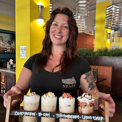 Smiling server with a flight of iced cofee.
