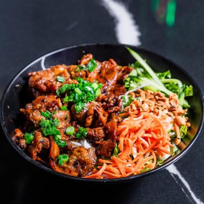Grilled meat bowl with vegetables, peanuts, and shredded carrots.