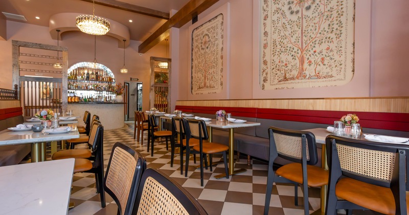 An elegant interior with checkered floors, floral artwork, and a bar at the back