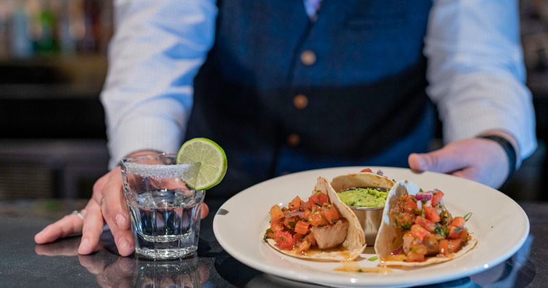 Staff serves a taco plate and a glass of drink, closeup