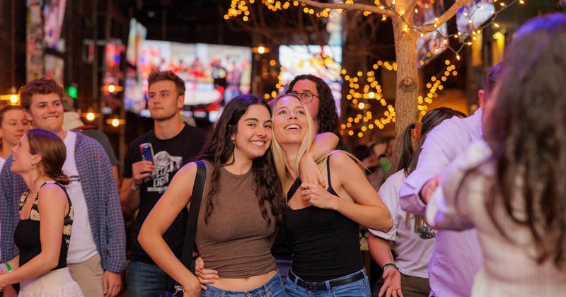 Lively outdoor patio scene with people posing and string lightning decorations