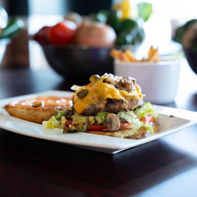 Cheeseburger with jalapenos, lettuce, tomato, and sauce.