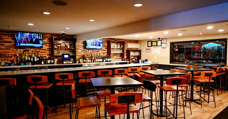 Seating area, tables with bar stools and a bar