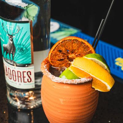 Paloma cocktail served in a clay cup with citrus garnish and salted rim.