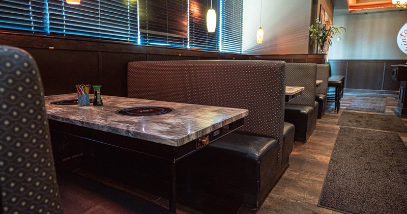 Cozy restaurant interior with dark, cushioned booths and marble-top tables