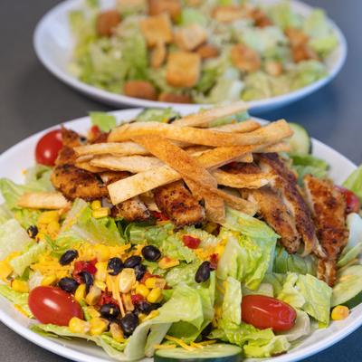 Southwest chicken salad and Caesar salad on a table.