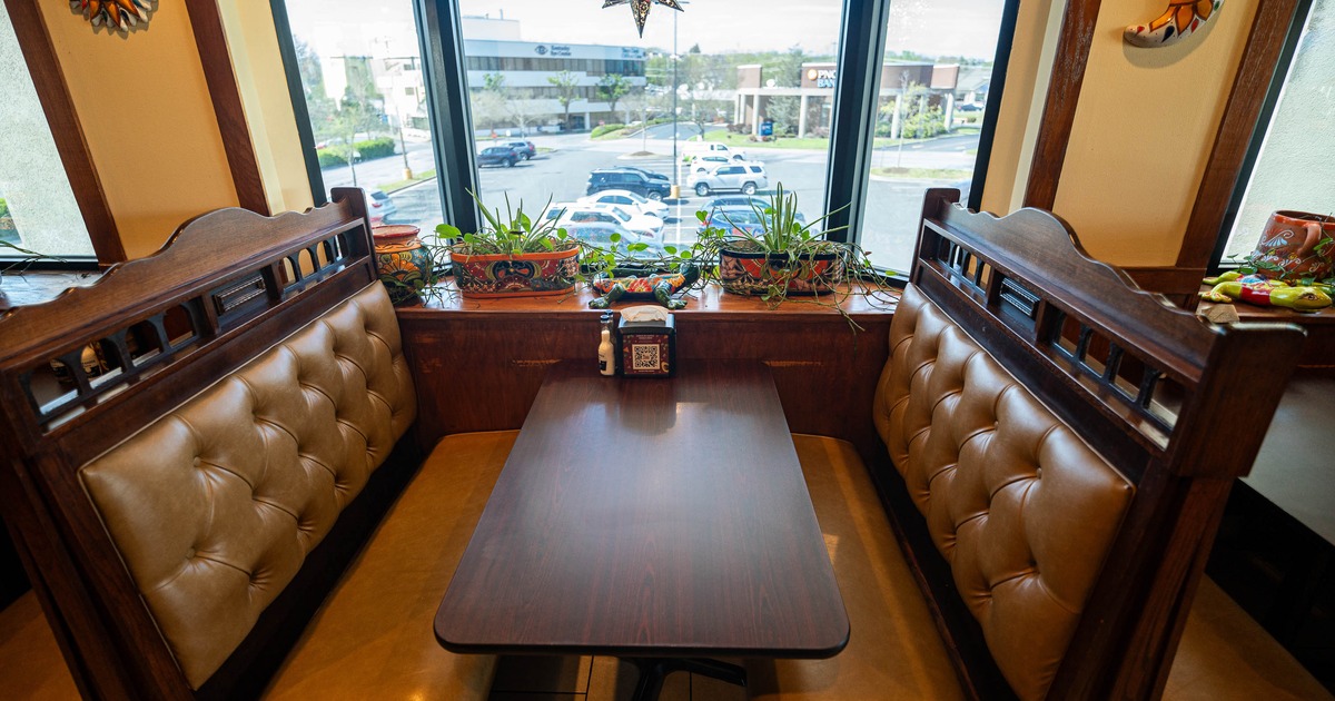 Cozy restaurant booth with tan leather seats and a dark wood table