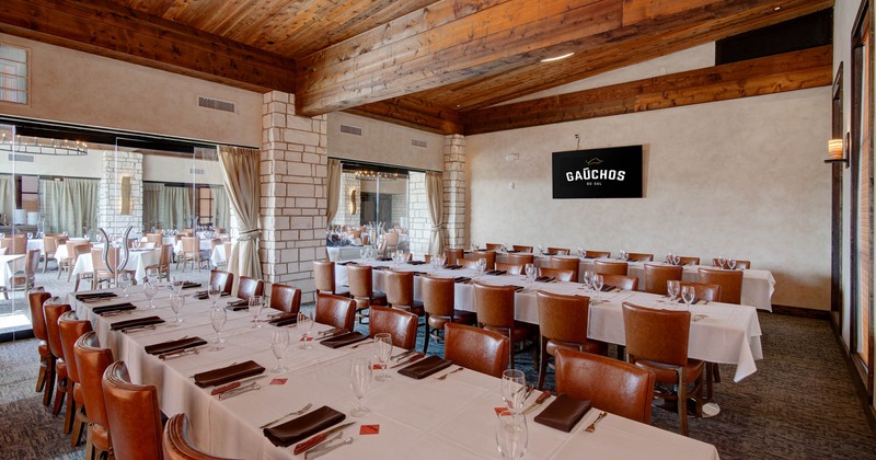 Interior, lined up set tables with table cloths, wine glasses, napkins, and cutlery