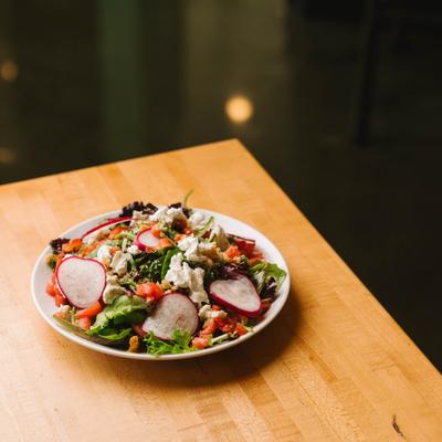 House salad with radishes and mixed greens, served on a wooden table.