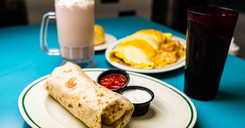 Breakfst burrito and omelet plates with drinks
