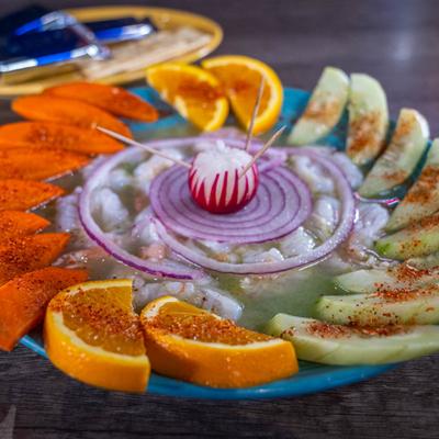 Plate of shrimp, cucumbers, orange slices, and chili powder.