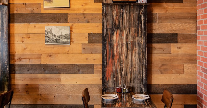 A dining table for two placed against a wooden decorative wall