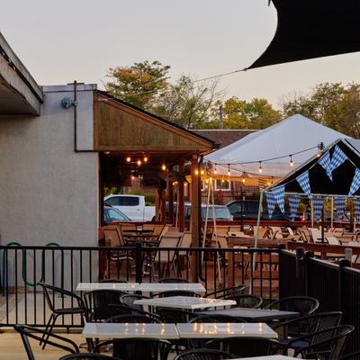 Outdoor seating area with tables and chairs, protected with sun shade sails.