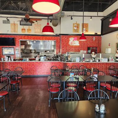 Dining area, service counter with red tiled walls and red pendant lighting fixtures.