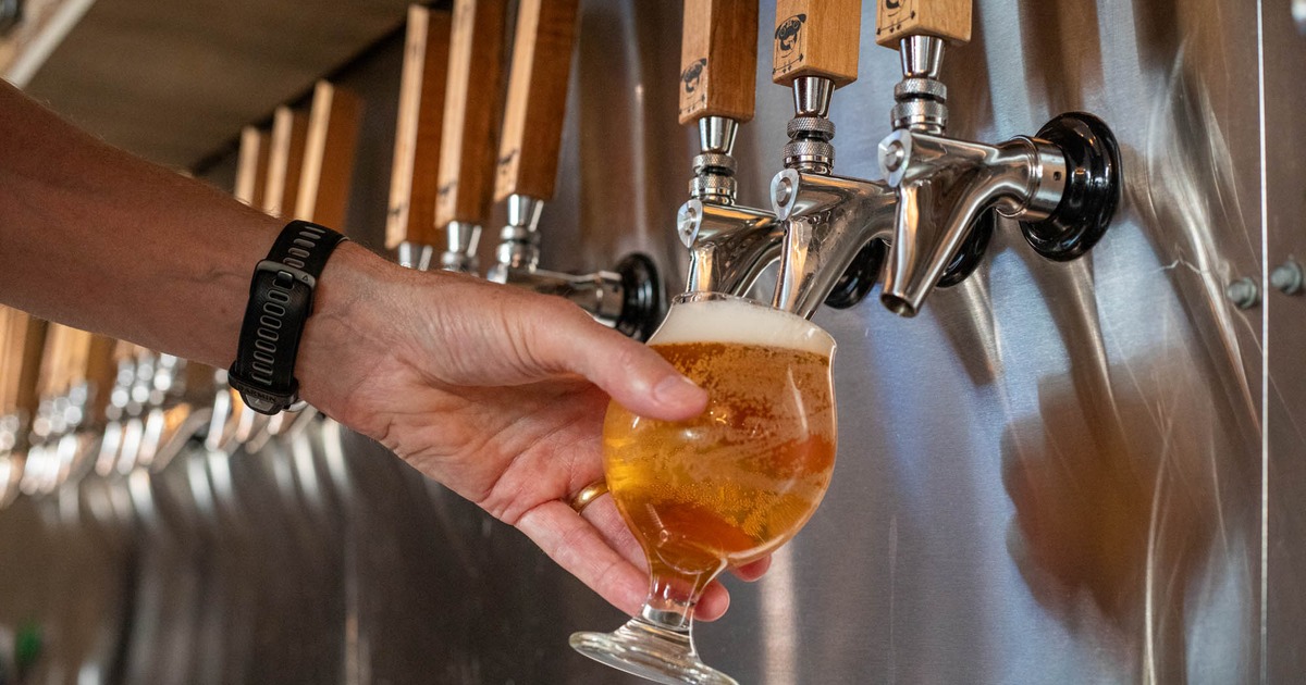 A person pours beer into a glass from a tap