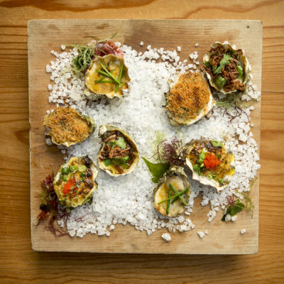 a variety of baked oysters displayed on salt and a wood board