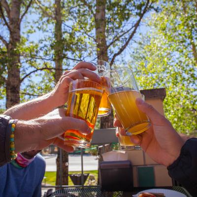 A moment where several people are making a toast outdoors with glasses of beer.