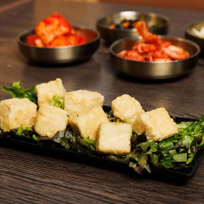 Fried tofu served over lettuce, alongside other dishes on the table.
