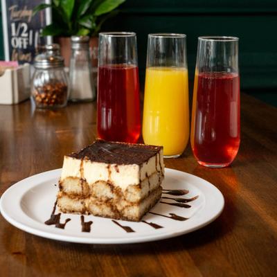 Slice of tiramisu served with mimosas on a restaurant table.