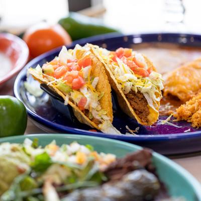 Crispy tacos served on a blue plate with sides.