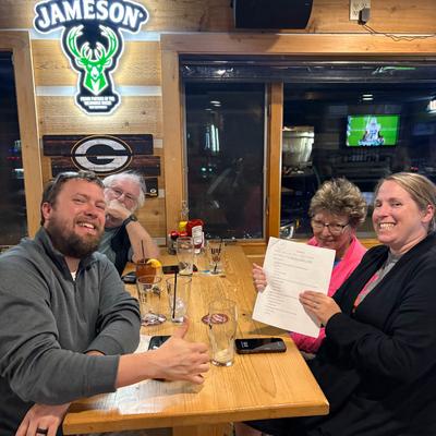 Group of four people smiling at a pub table with drinks.