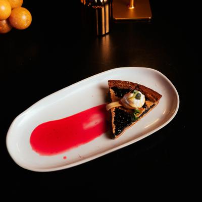 Blueberry tart topped with ice cream and raspberry sauce.