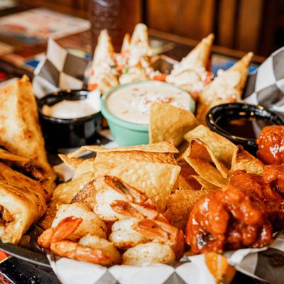 Appetizer platter with wings, shrimp, chips, and dipping sauces.
