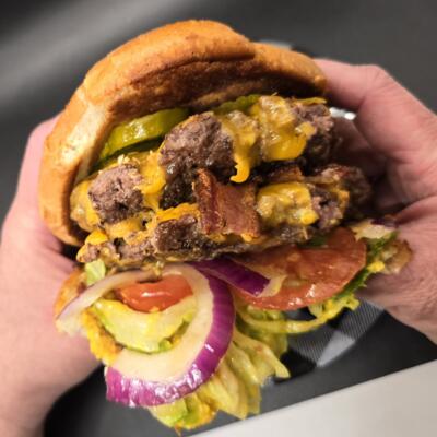 Close-up of a juicy cheeseburger in hands.