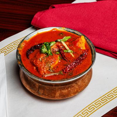 Spicy fish curry in a hammered copper bowl.
