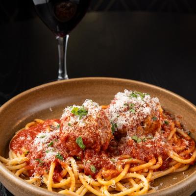 Pasta and Meatballs served on the tabke with a glass of red wine.