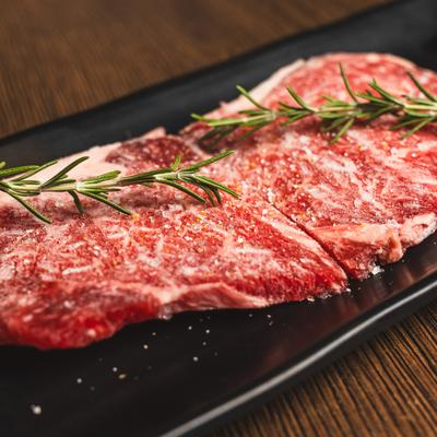 Raw Ribeye seasoned with salt and garnished with fresh rosemary.