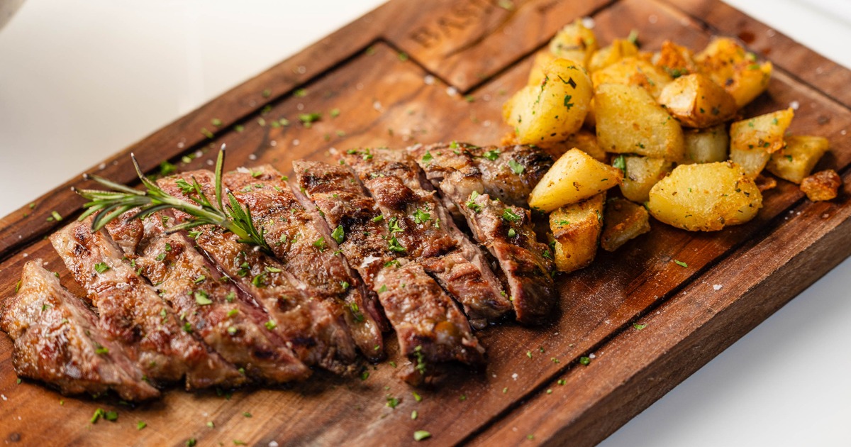 Grilled and sliced steak with a side of roasted potatoes