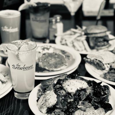 Black-and-white photo of plated meals and drinks on a restaurant table.