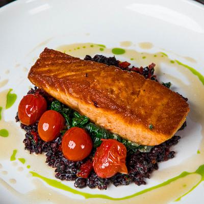 Pan seared salmon served over sauteed spinach, with wild rice and poached tomatoes.
