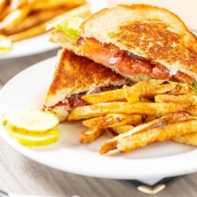 BLT sandwich with fries and pickle.