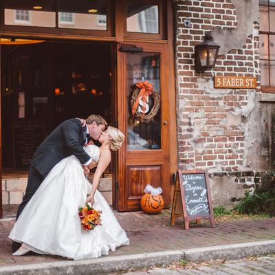 Newlyweds kissing outside a rustic brick venue.