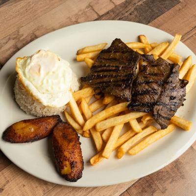 Skirt steak with chimichurri sauce, egg, rice, French fries and sweet plantain.