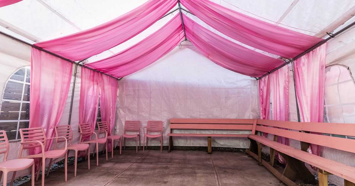 Interior of a pink and white tent with pink seating and a disco ball