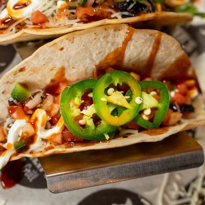 Smoked brisket taco, with cheese, tomato salsa, jalapenos, sour cream, and BBQ sauce.