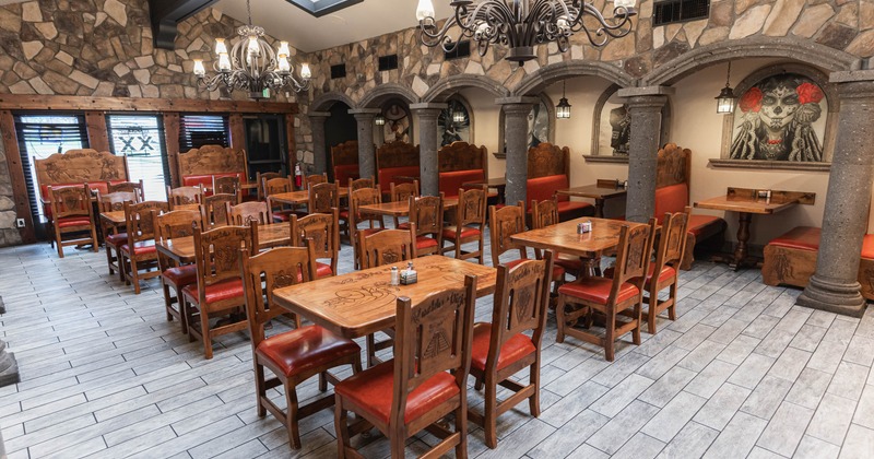 Interior with wooden furniture, stone walls, chandeliers and decorative artwork