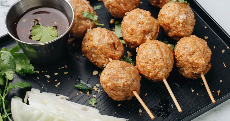 Homemade Fried Meatballs served with sweet chili dip, cabbage and basil