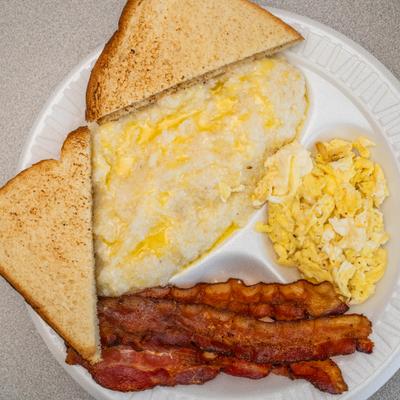 Breakfast plate with grits, scrambled eggs, bacon and toast.