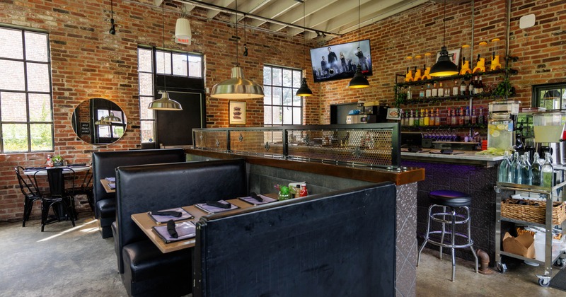Interior seating area with exposed brick walls, and black leather booths
