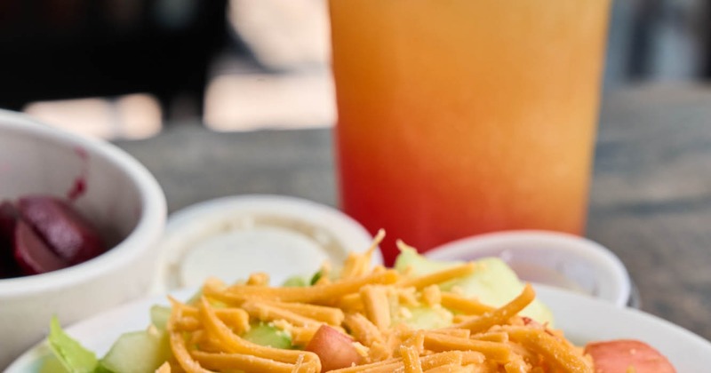 Salad with lettuce, chopped tomatoes, and shredded cheese, accompanied with an orange cocktail