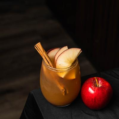 Fallen apple cocktail garnished with apple slices and cinnamon stick.