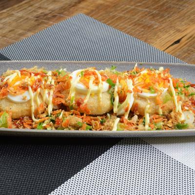 A plate of sushi rolls topped with creamy sauce.