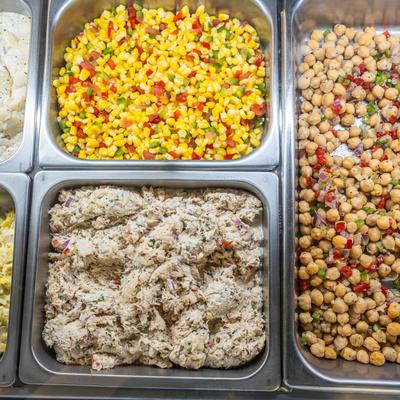 Chickpeas salad, tuna salad, and corn salad in metal trays.