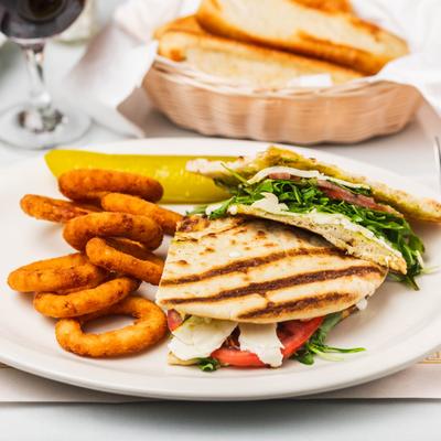 Caprese Sandwich, with tomato, mozzarella, pesto, arugula, balsamic, and a side of onion rings.