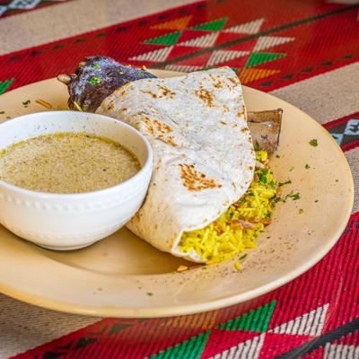 Lamb shank served over rice with toasted almonds, bread and yogurt sauce.